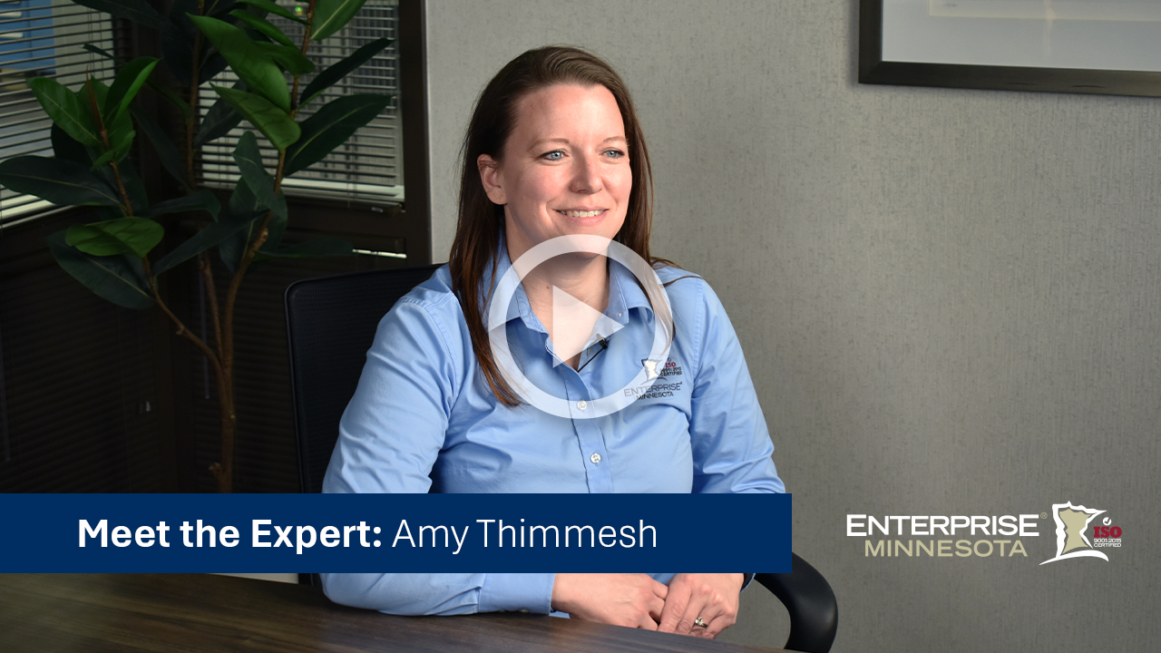 Amy Thimmesh sitting in a chair. Click to watch her bio video. 