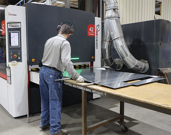 Sheet metal worker feeding an aluminum processing machine.